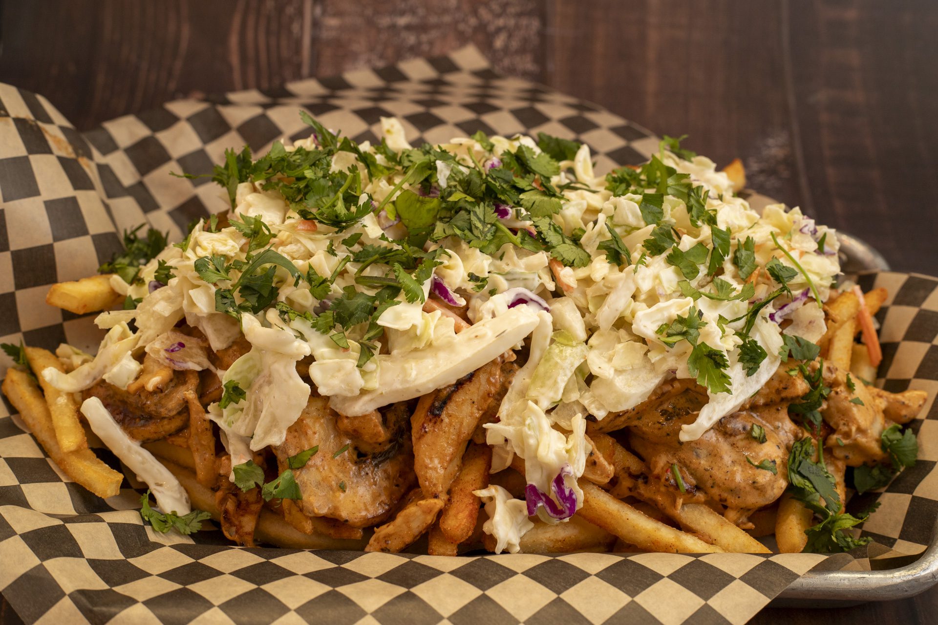 Loaded fries topped with chicken, sauce, and fresh herbs.