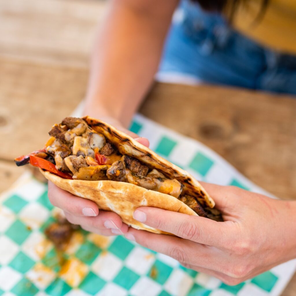 Person holding a grilled chicken quesadilla with melted cheese.